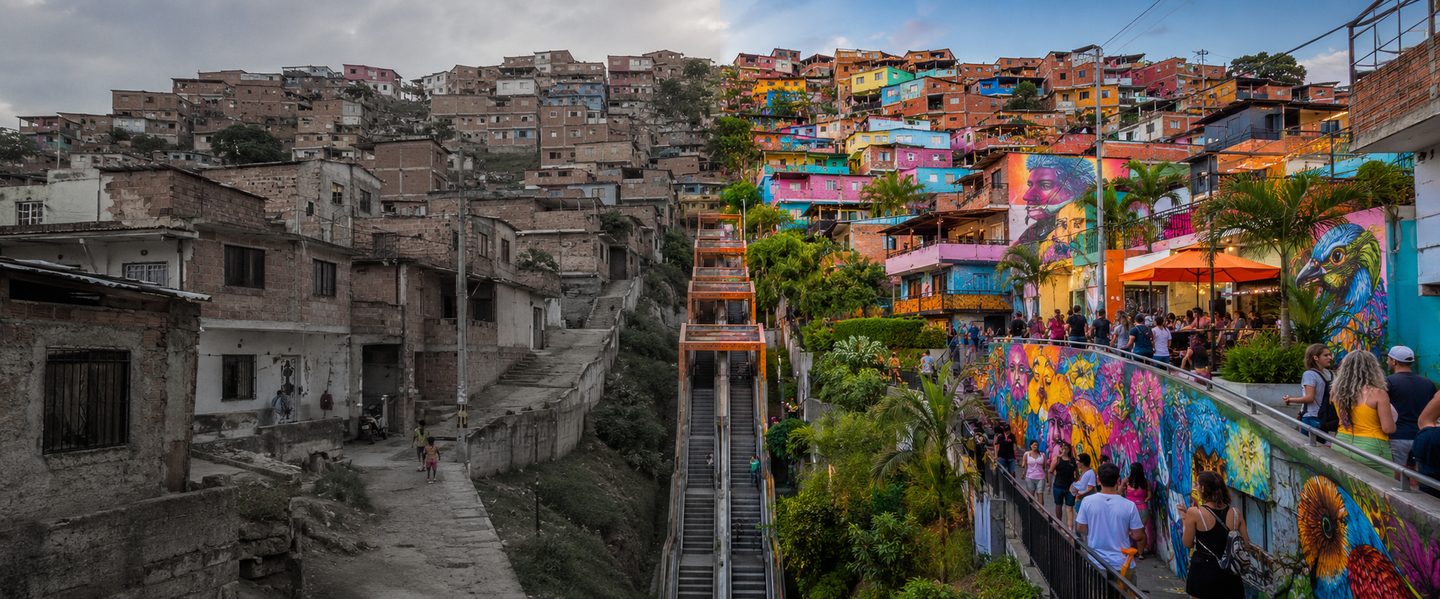 Split view of Comuna 13 transformation — from gray concrete barrio to vibrant colorful murals and community life
